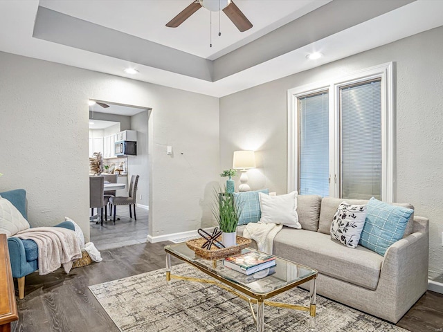 living room featuring ceiling fan and dark hardwood / wood-style floors