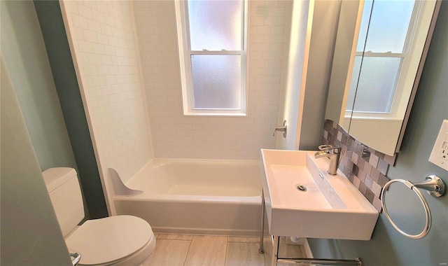 full bathroom featuring sink, tiled shower / bath combo, tasteful backsplash, tile patterned flooring, and toilet