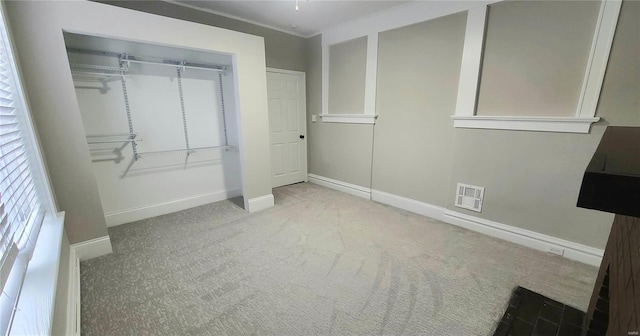 unfurnished bedroom featuring a closet, light colored carpet, and ornamental molding