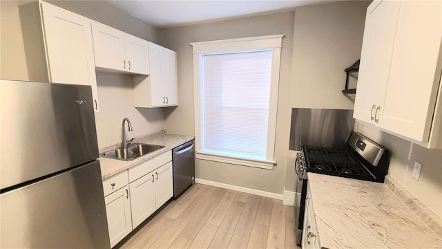 kitchen with white cabinetry, sink, appliances with stainless steel finishes, and light hardwood / wood-style flooring