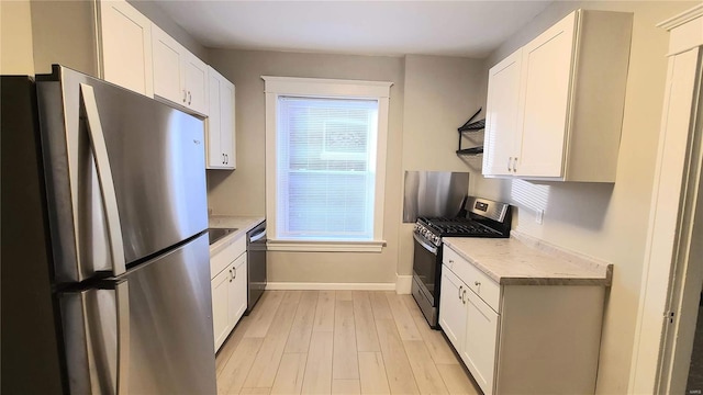 kitchen with appliances with stainless steel finishes, light wood-type flooring, light stone counters, extractor fan, and white cabinetry