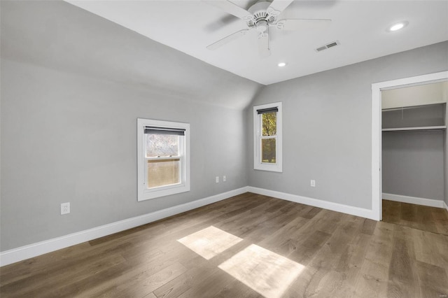 unfurnished bedroom featuring multiple windows, ceiling fan, vaulted ceiling, and hardwood / wood-style flooring