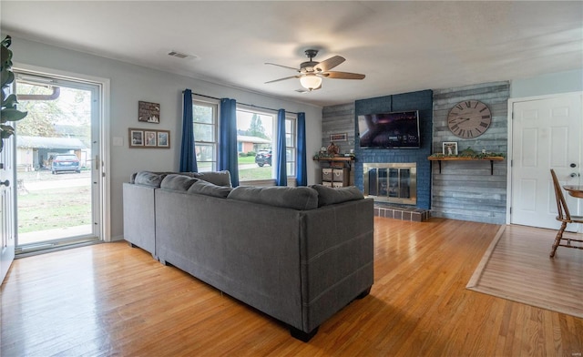 living room featuring a large fireplace, a healthy amount of sunlight, and hardwood / wood-style floors