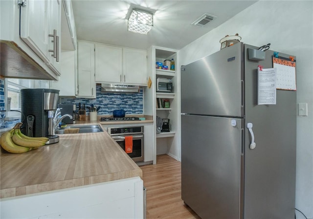 kitchen featuring white cabinetry, sink, stainless steel appliances, backsplash, and light hardwood / wood-style floors