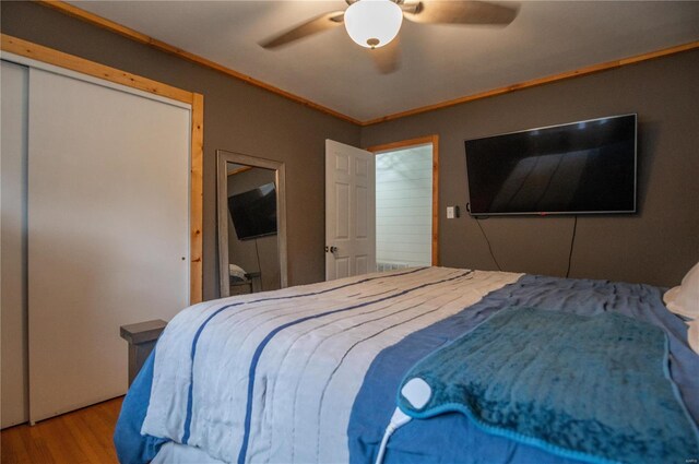 bedroom featuring wood-type flooring, a closet, ceiling fan, and crown molding