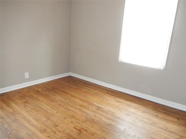 spare room with baseboards and light wood finished floors