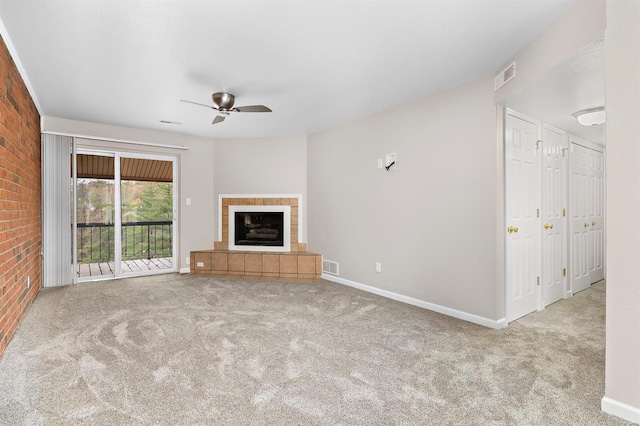 unfurnished living room with ceiling fan, brick wall, light carpet, and a tile fireplace