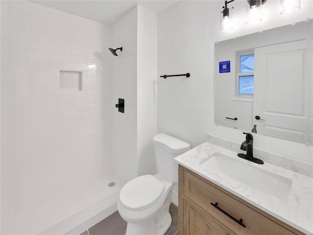 bathroom with vanity, toilet, and tiled shower