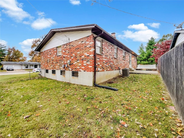 view of side of property featuring a lawn and central AC