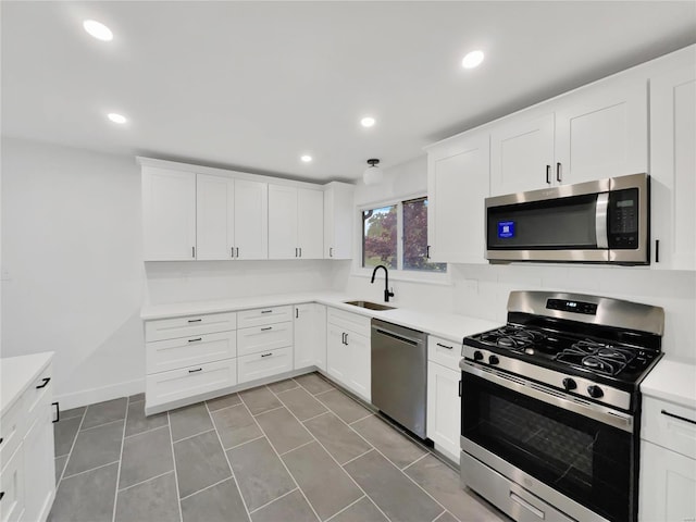 kitchen with appliances with stainless steel finishes, white cabinetry, tile patterned floors, and sink