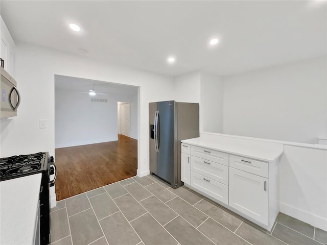 kitchen with ceiling fan, white cabinets, light hardwood / wood-style floors, and appliances with stainless steel finishes