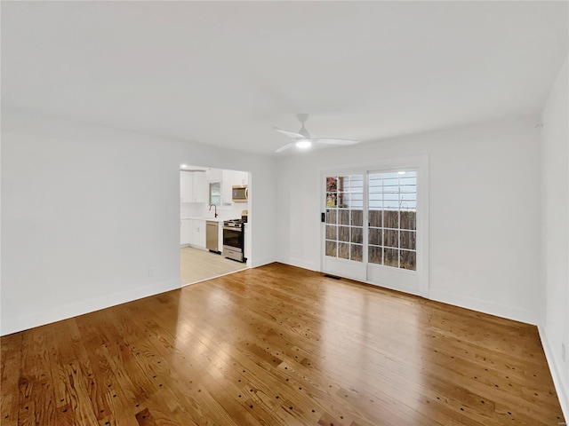 empty room with light hardwood / wood-style floors, ceiling fan, and sink