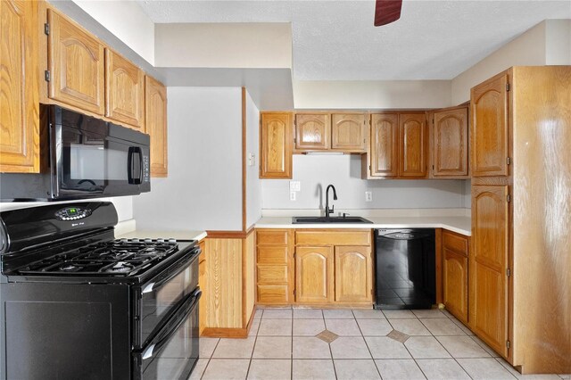 kitchen with sink, light tile patterned floors, black appliances, and a textured ceiling