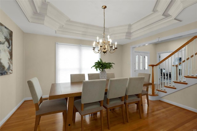 dining room featuring plenty of natural light, a raised ceiling, wood-type flooring, and an inviting chandelier