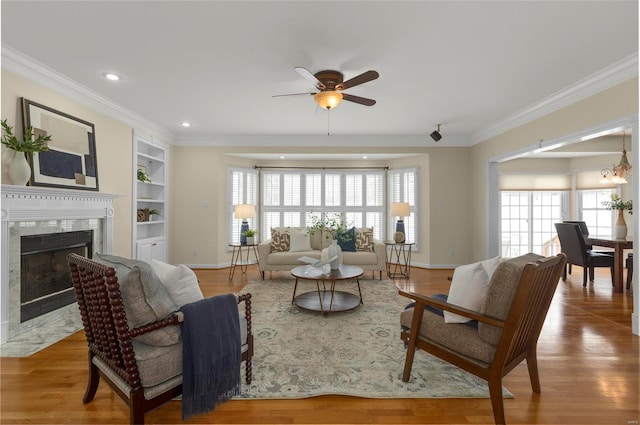 living room with a healthy amount of sunlight, ceiling fan, built in shelves, and a fireplace