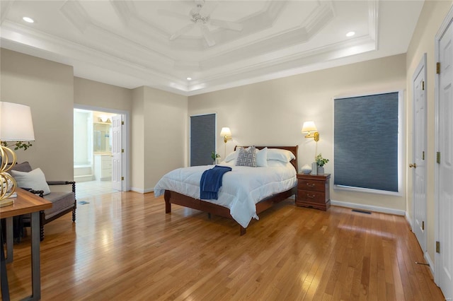 bedroom featuring light hardwood / wood-style flooring, a raised ceiling, connected bathroom, crown molding, and ceiling fan