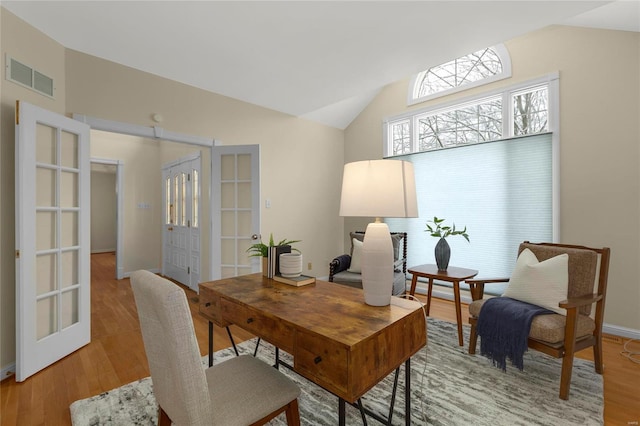 office with lofted ceiling, french doors, and light hardwood / wood-style floors