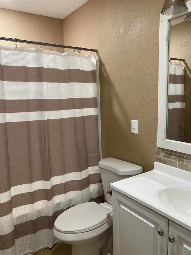 bathroom with vanity, toilet, and tasteful backsplash