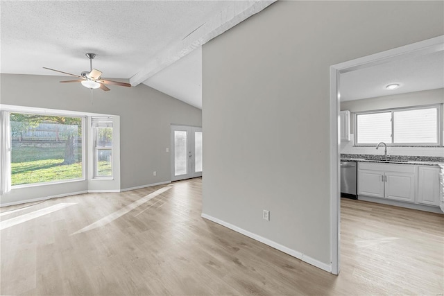 unfurnished living room featuring lofted ceiling with beams, light hardwood / wood-style floors, a textured ceiling, and ceiling fan