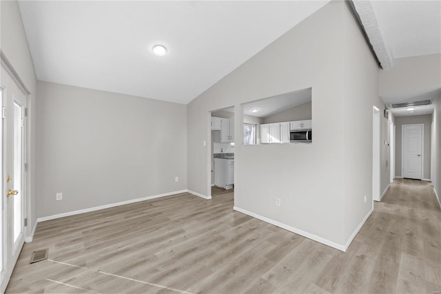 unfurnished living room with light wood-type flooring, plenty of natural light, and lofted ceiling