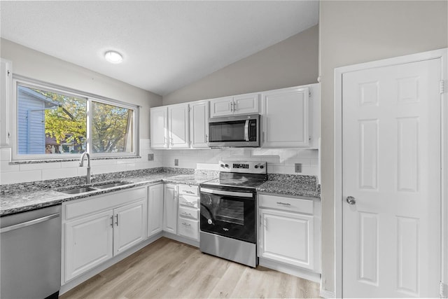 kitchen featuring white cabinets, lofted ceiling, stainless steel appliances, and tasteful backsplash