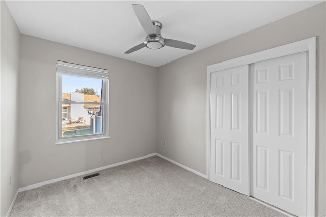 unfurnished bedroom with ceiling fan, a closet, and light colored carpet