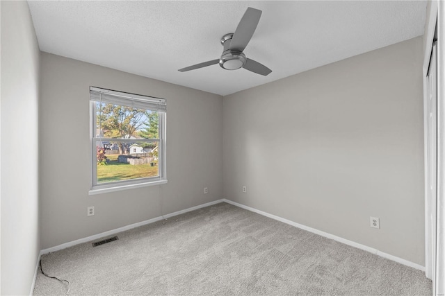 spare room featuring ceiling fan, light colored carpet, and a textured ceiling