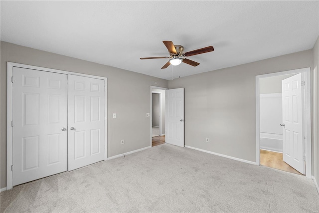 unfurnished bedroom with ceiling fan, ensuite bath, light carpet, and a closet