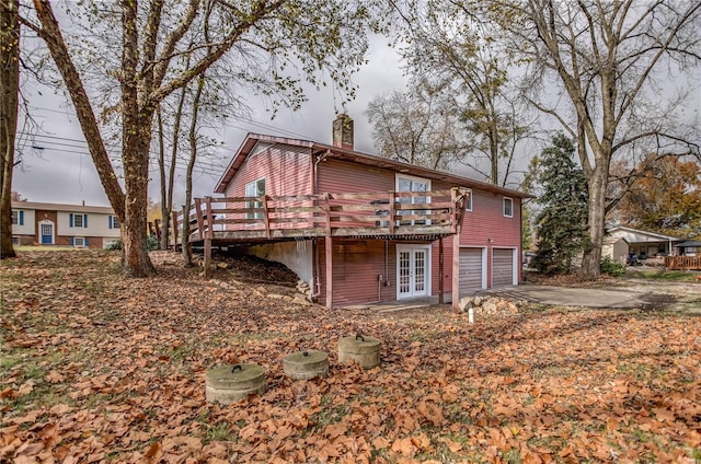 back of property featuring a garage, a wooden deck, and french doors