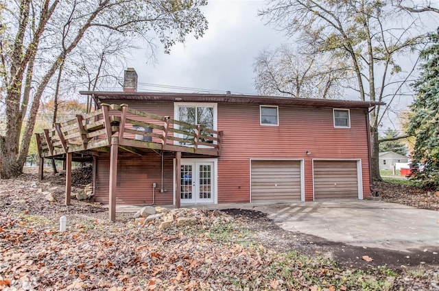 rear view of house with a wooden deck, french doors, and a garage