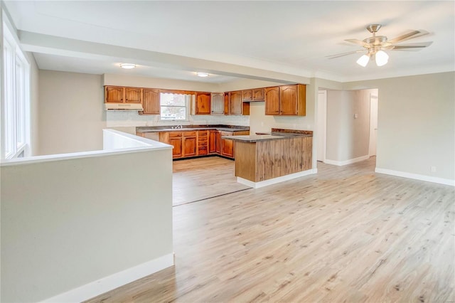 kitchen featuring kitchen peninsula, ceiling fan, sink, and light wood-type flooring