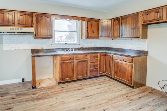 kitchen with sink, light wood-type flooring, backsplash, and exhaust hood