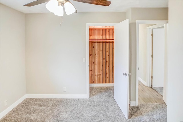 unfurnished bedroom with light colored carpet, a spacious closet, a closet, and ceiling fan