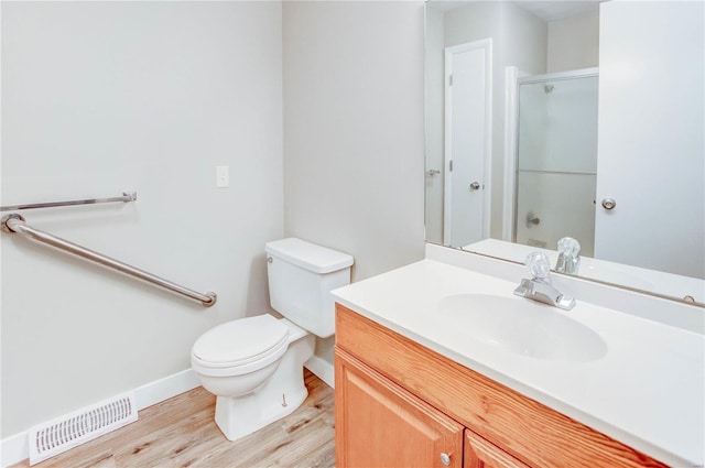 bathroom with hardwood / wood-style flooring, vanity, toilet, and a shower with shower door