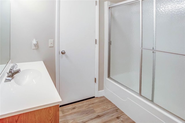 bathroom with hardwood / wood-style flooring, vanity, and bath / shower combo with glass door