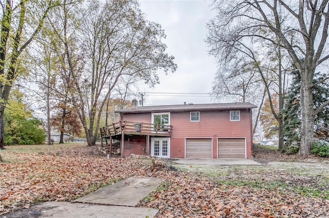 rear view of property featuring a wooden deck, french doors, and a garage