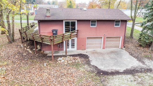 rear view of house with a garage, a wooden deck, and french doors