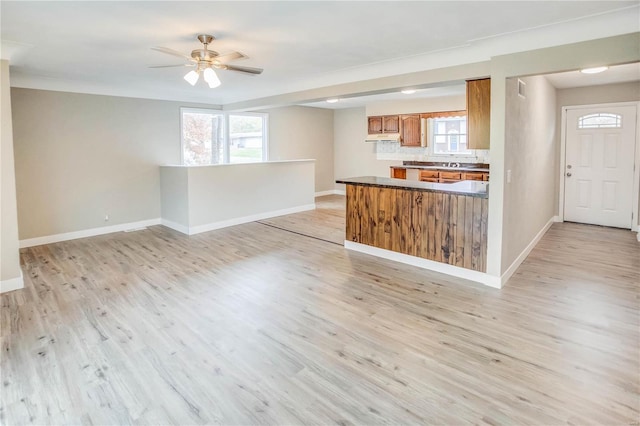 kitchen featuring backsplash, kitchen peninsula, ceiling fan, and light wood-type flooring