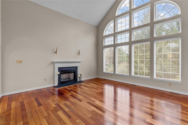 unfurnished living room with hardwood / wood-style floors and high vaulted ceiling