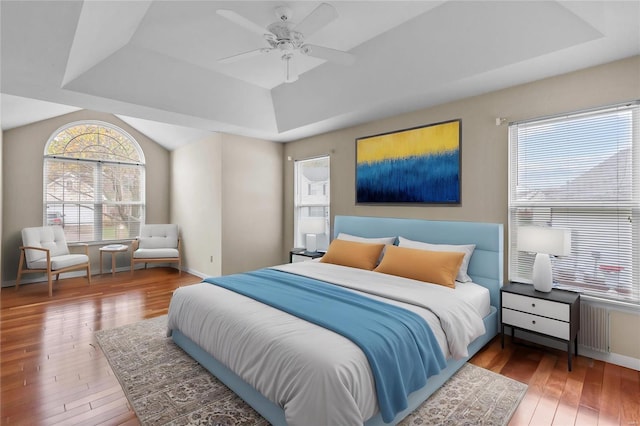 bedroom with a raised ceiling, ceiling fan, and hardwood / wood-style flooring