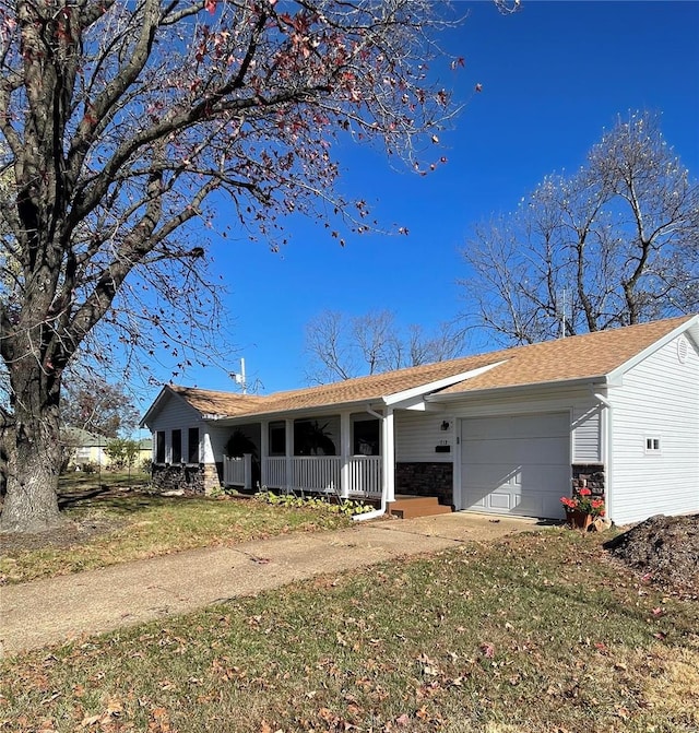 ranch-style house with covered porch, a front yard, and a garage