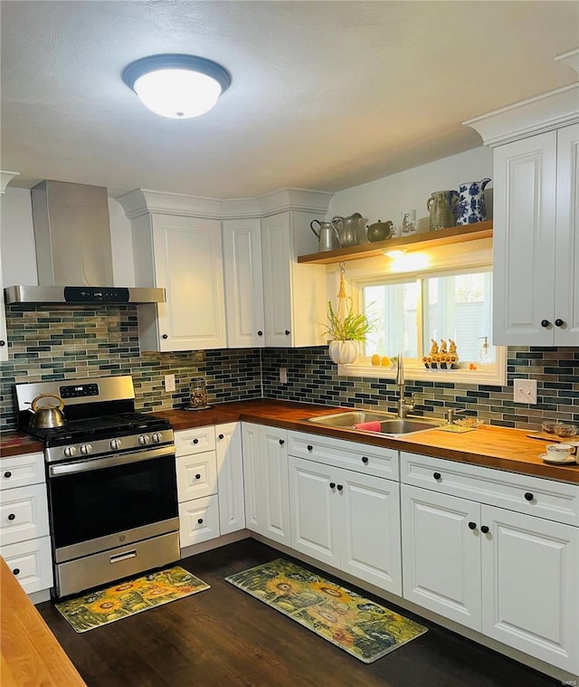 kitchen featuring wooden counters, stainless steel range oven, white cabinetry, and wall chimney range hood