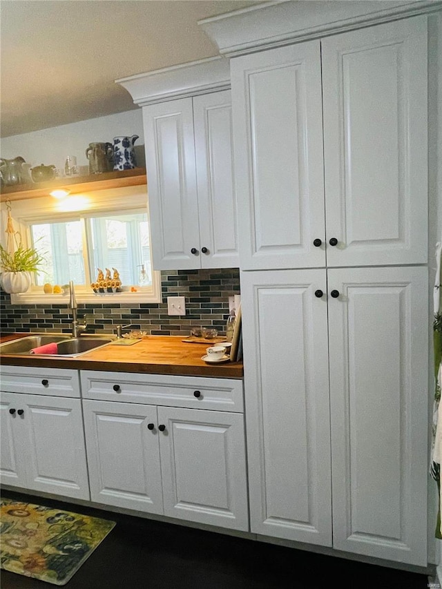 bar featuring white cabinets, decorative backsplash, sink, and wooden counters