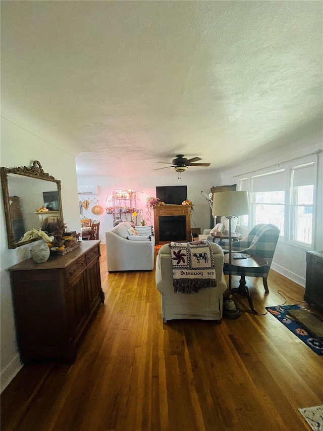 living room with hardwood / wood-style flooring, ceiling fan, and a textured ceiling