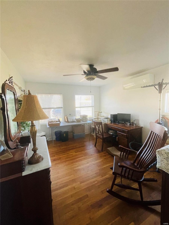 living area with a wall unit AC, ceiling fan, and wood-type flooring