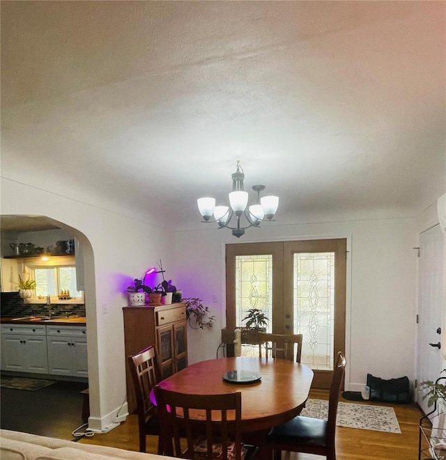 dining space with a chandelier, french doors, dark wood-type flooring, and sink