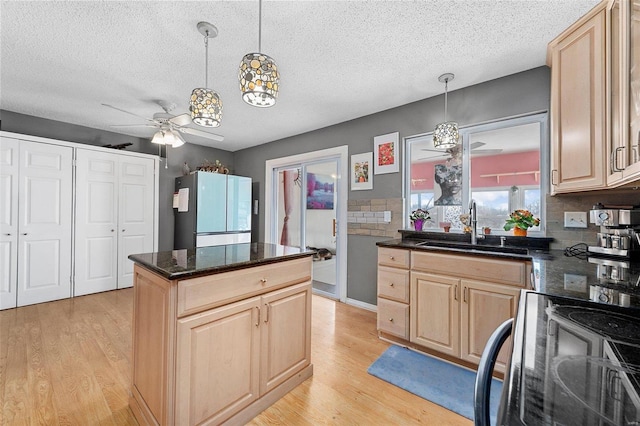 kitchen with light brown cabinets, a sink, and freestanding refrigerator