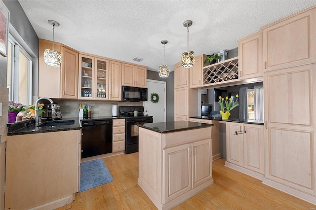 kitchen featuring light wood-style flooring, a sink, visible vents, light brown cabinetry, and black appliances