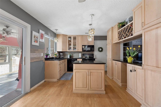 kitchen featuring light wood-type flooring, a center island, black appliances, and light brown cabinetry