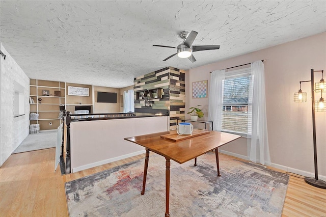 office featuring a ceiling fan, a textured ceiling, baseboards, and wood finished floors